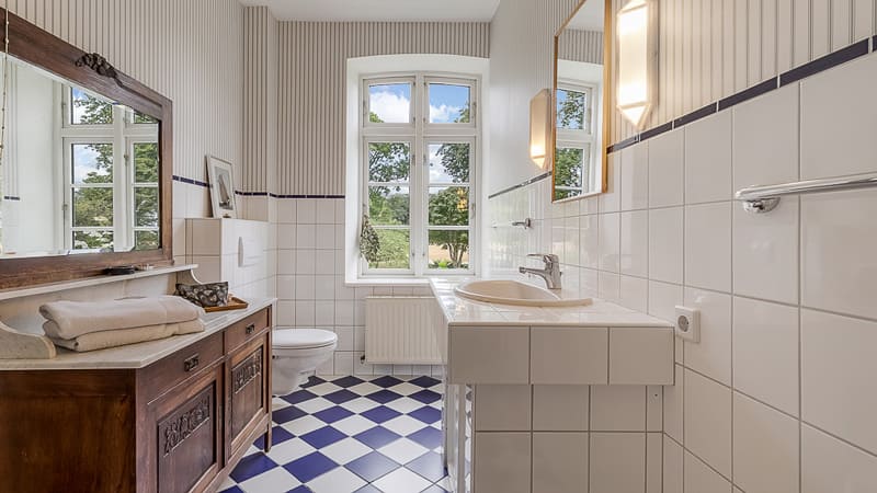 Immobilienfotografie für München - Landhaus Badezimmer Foto mit Blick zum Fenster und Schachbrett Fliesen in blau - weiss