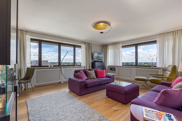 Architekturfotograf aus Hamburg Apartment im Mundsburg Tower - Wohnzimmer mit lila Polstermöbeln und grauem Teppich