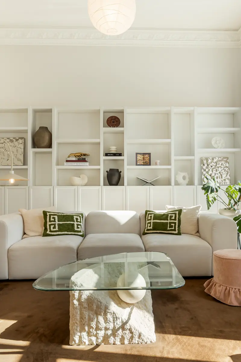 Helles Wohnzimmer im Altbau mit Stuckdecke, Regalwand und Sofa