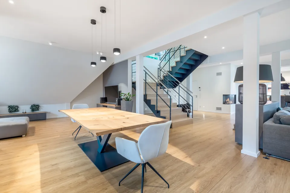 Fertige Wohnung: offener Wohn- und Essbereich mit Holztisch, Hängeleuchten und Treppe