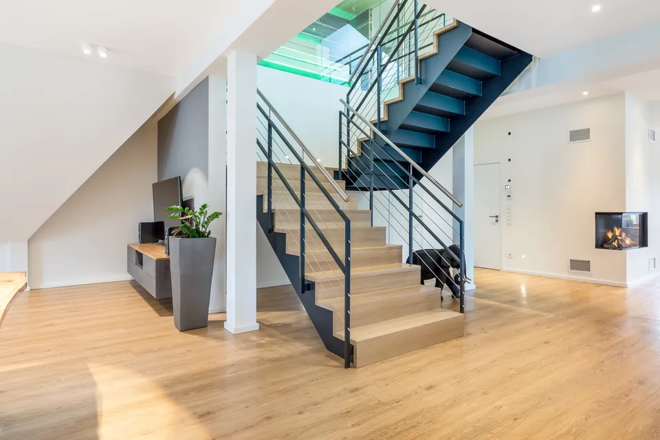Fertige Wohnung: Wohnbereich mit Treppe aus Holz und Stahl und Eckkamin