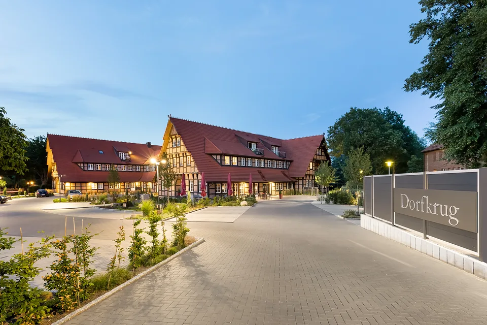 Fachwerk-Ensemble am Abend mit beleuchteter Zufahrt und Schriftzug