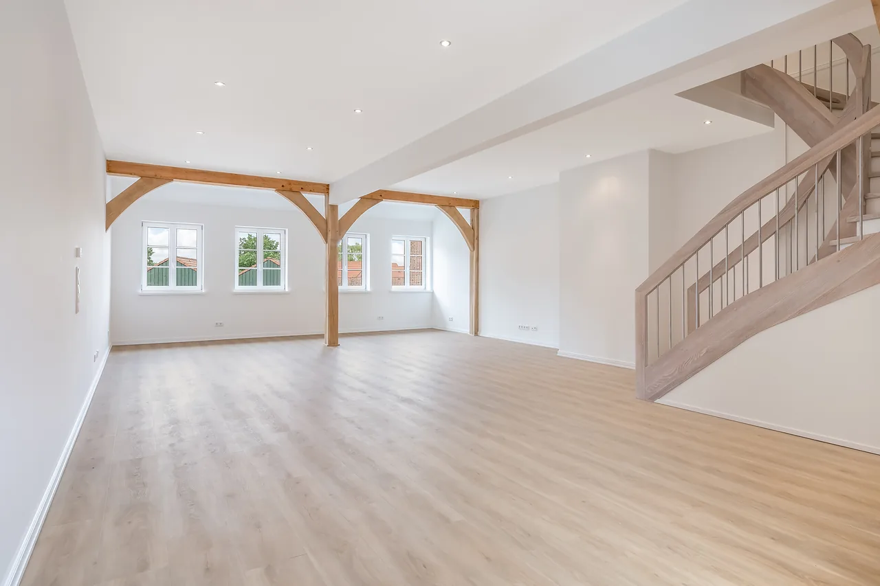 Fertig: heller Wohnraum mit erhaltenen Holzstützen, Vinylboden und Treppe
