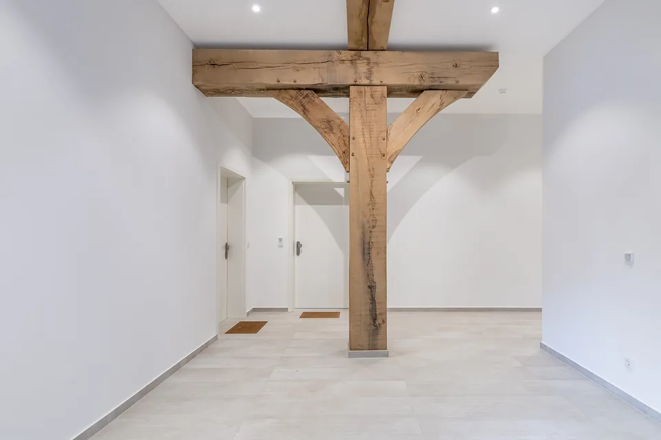Fertiges Treppenhaus mit erhaltener Holzstütze und hellem Boden