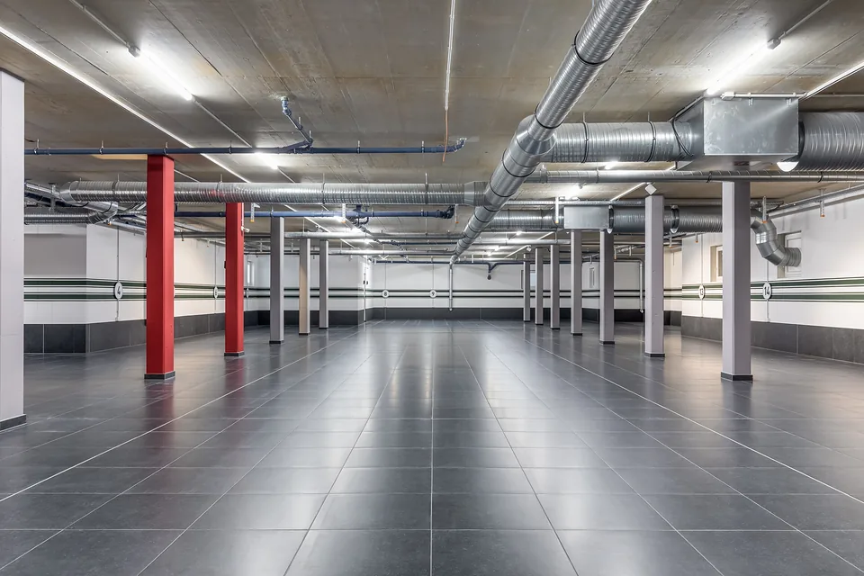 Fertige Tiefgarage mit roten Stützen und Leitungen an der Decke