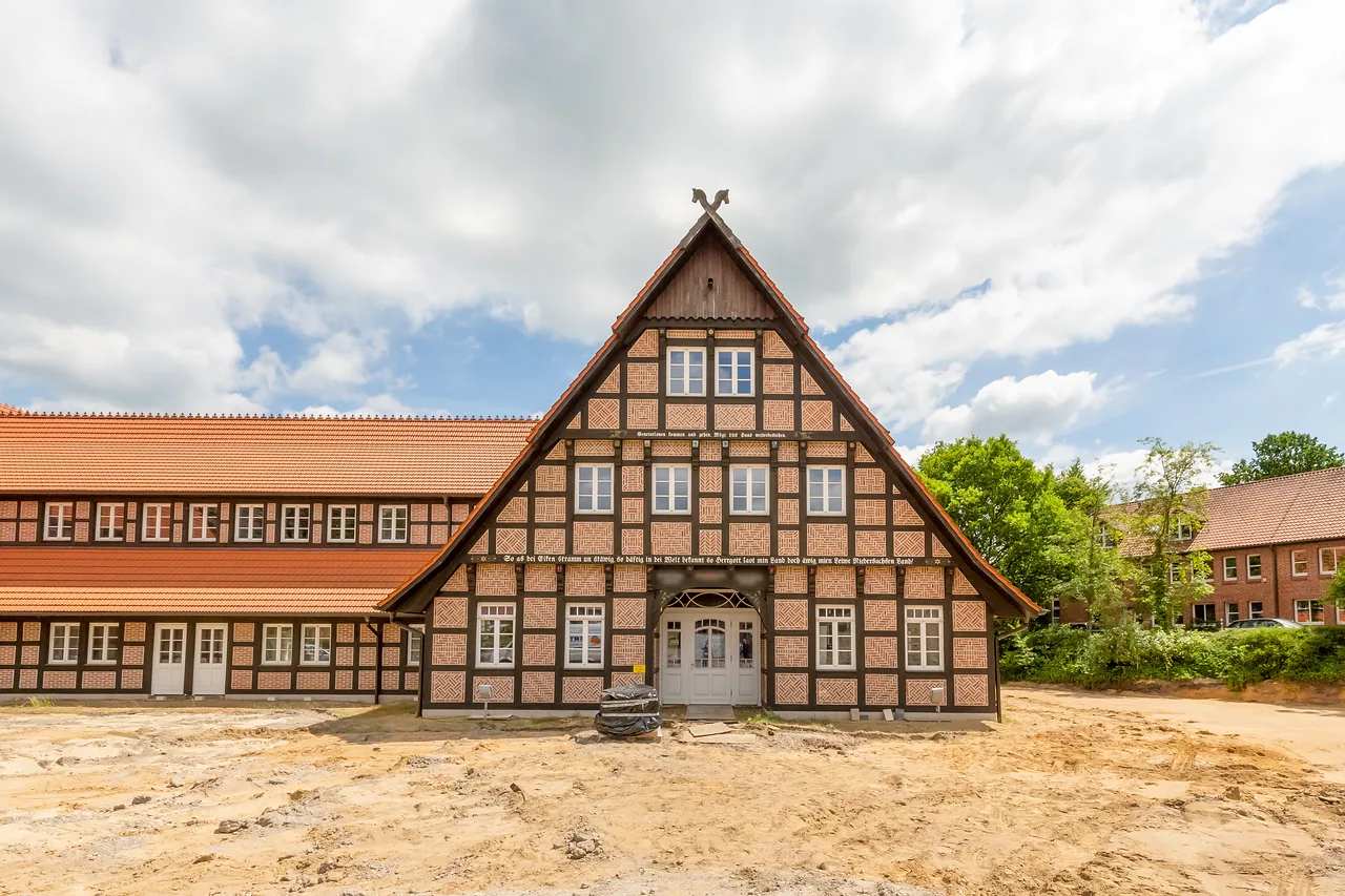 Rohbau: Fachwerkgiebel mit Torbogen, davor Sandfläche