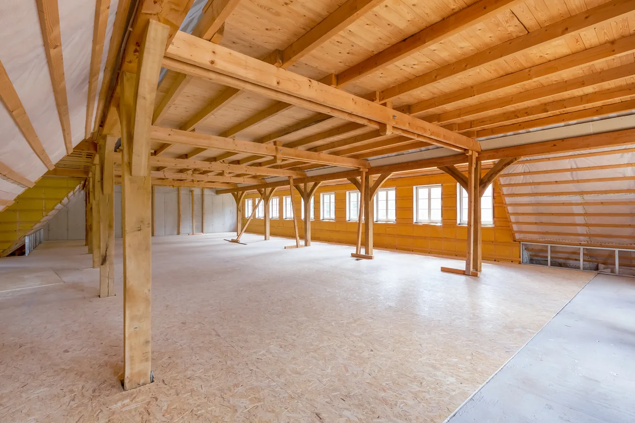 Rohbau: Dachgeschoss mit Holzständern, Unterzügen und Dachschräge