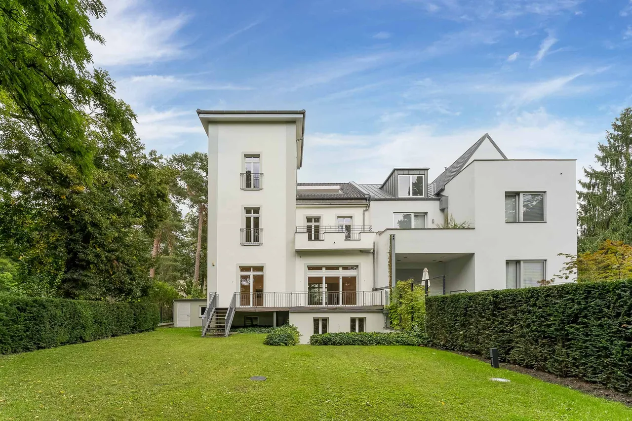 Nachher: Villa mit großem Rasen und Hecken unter blauem Himmel