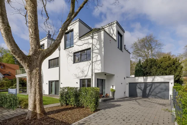 Weiße Stadtvilla mit Garage und altem Baum