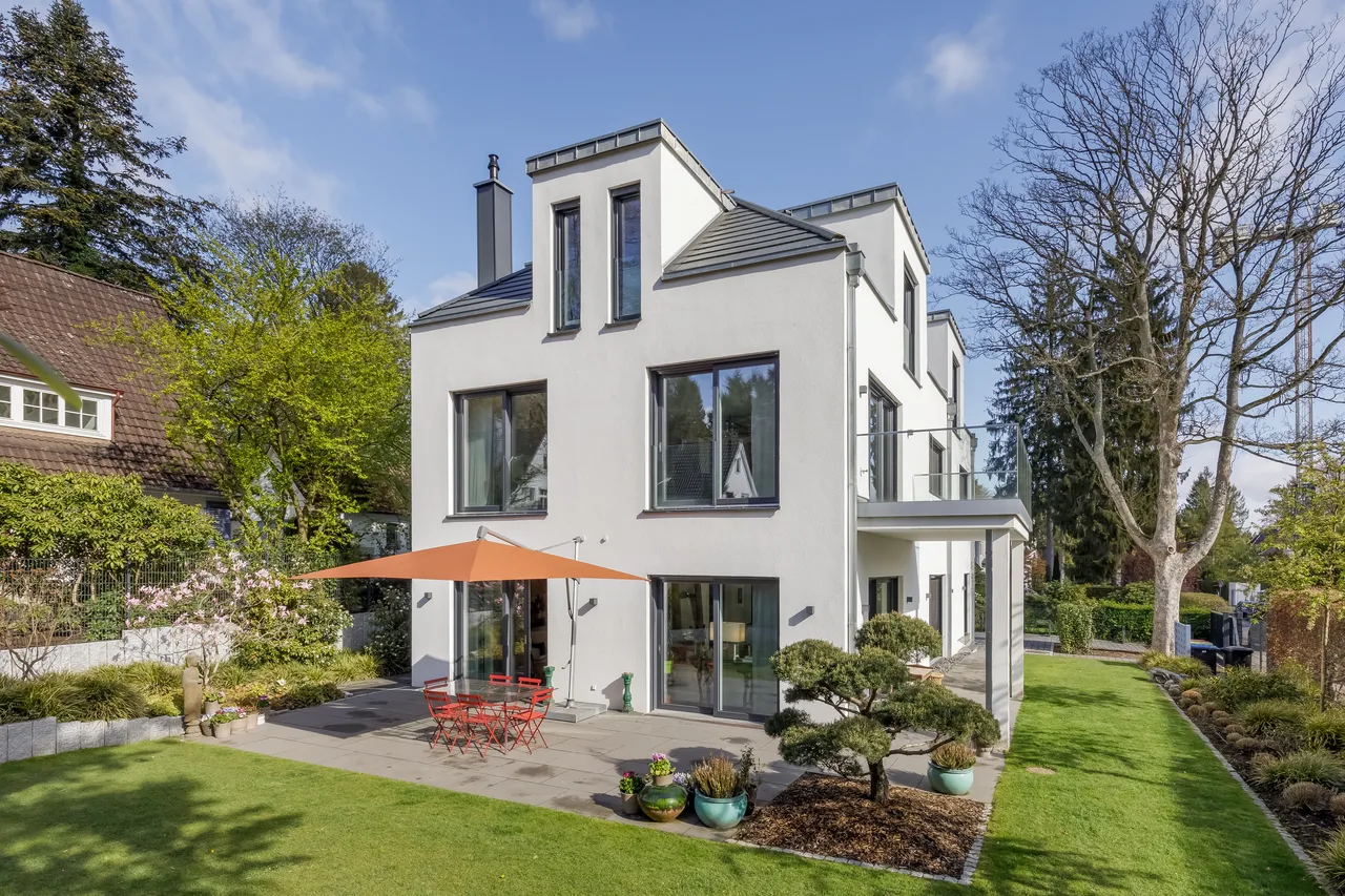 Weiße Stadtvilla mit Terrasse und Sonnenschirmen im Garten