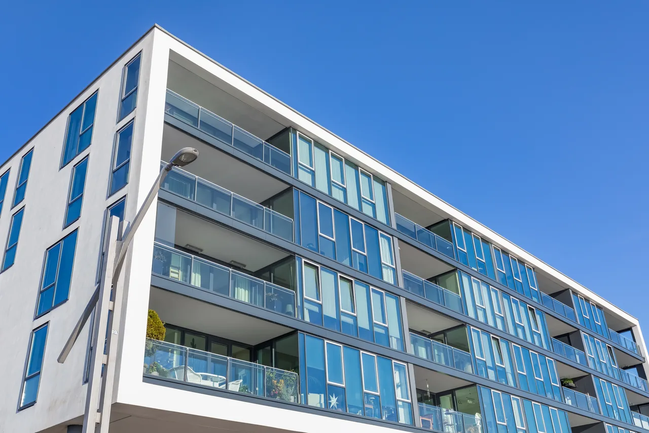 Moderne Wohnanlage mit verglasten Balkonen vor blauem Himmel