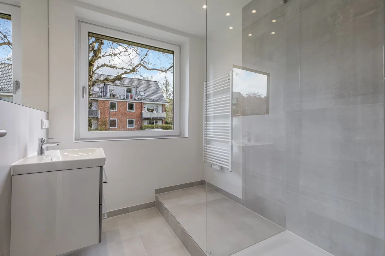Nachher: dasselbe Bad mit Dusche hinter Glas, Waschtisch mit Unterschrank und Handtuchheizkörper