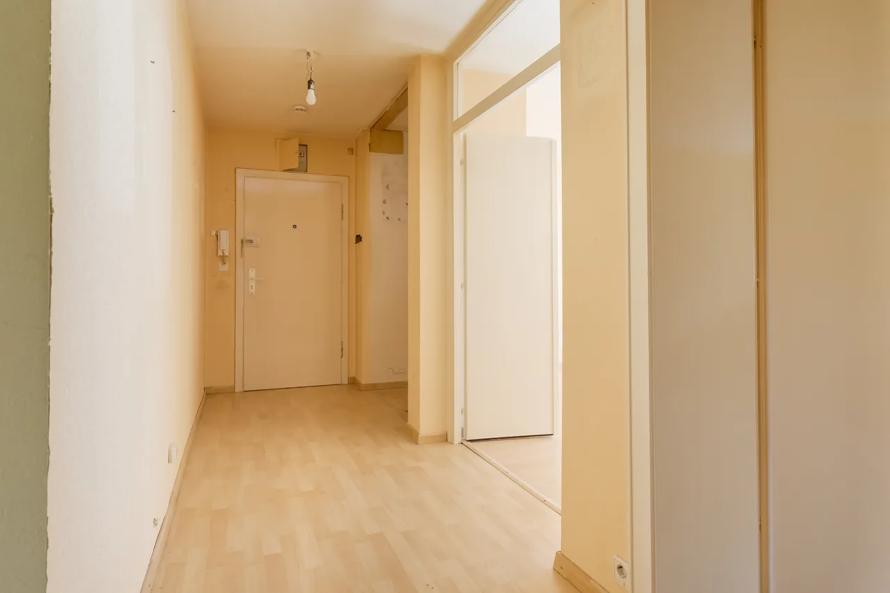 Vorher: Flur mit Holzverkleidung, gelben Wänden und alter Wohnungstür