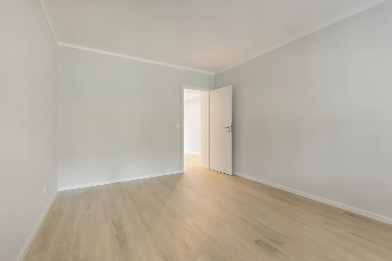 Nachher: dasselbe Zimmer mit hellen Wänden, neuem Boden und neuer Tür