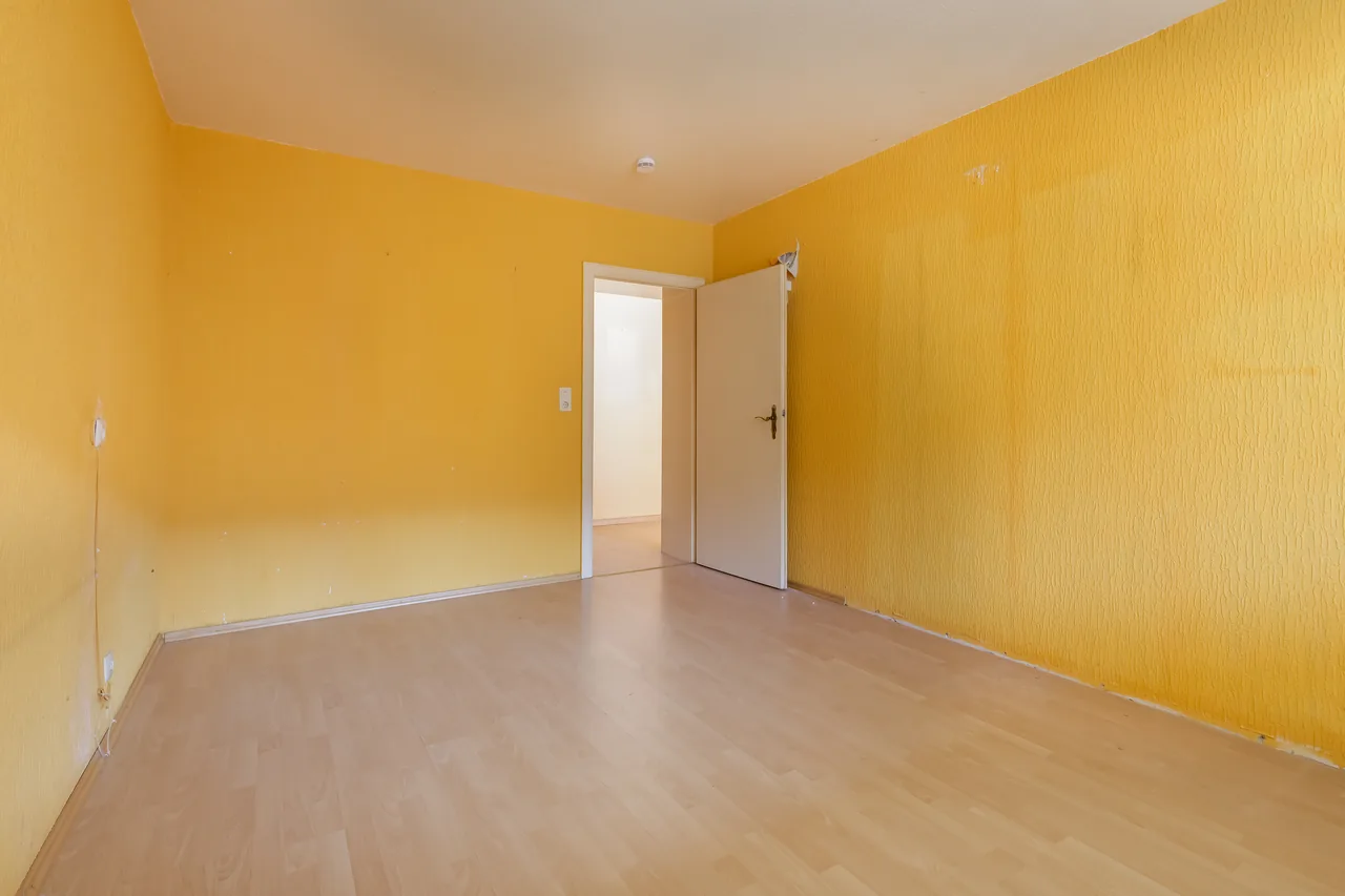 Vorher: Zimmer mit gelber Raufasertapete und altem Laminatboden