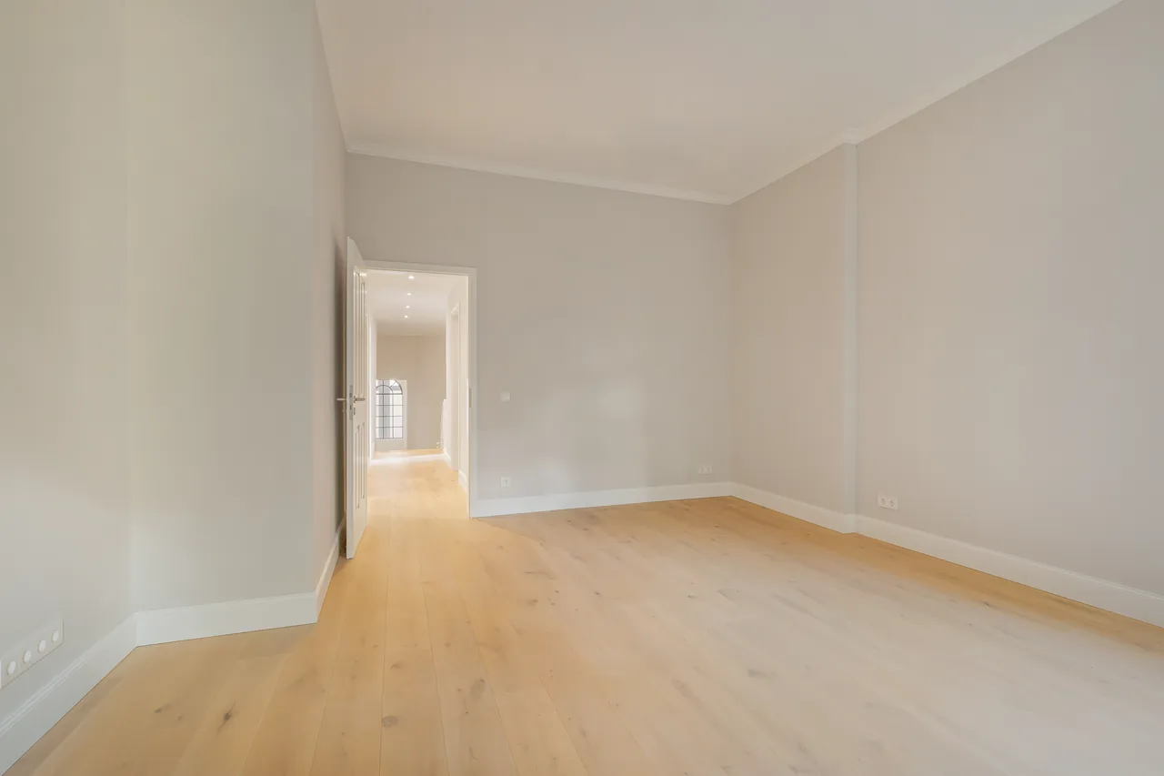 Nachher: dasselbe Zimmer mit neuem Holzboden, hellen Wänden und neuer Tür