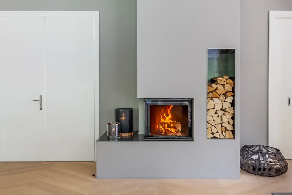 Moderner Kamin mit Holzfach in einer hellen Wand