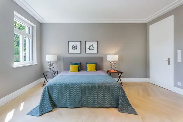Helles Schlafzimmer mit Doppelbett und Fischgrätparkett
